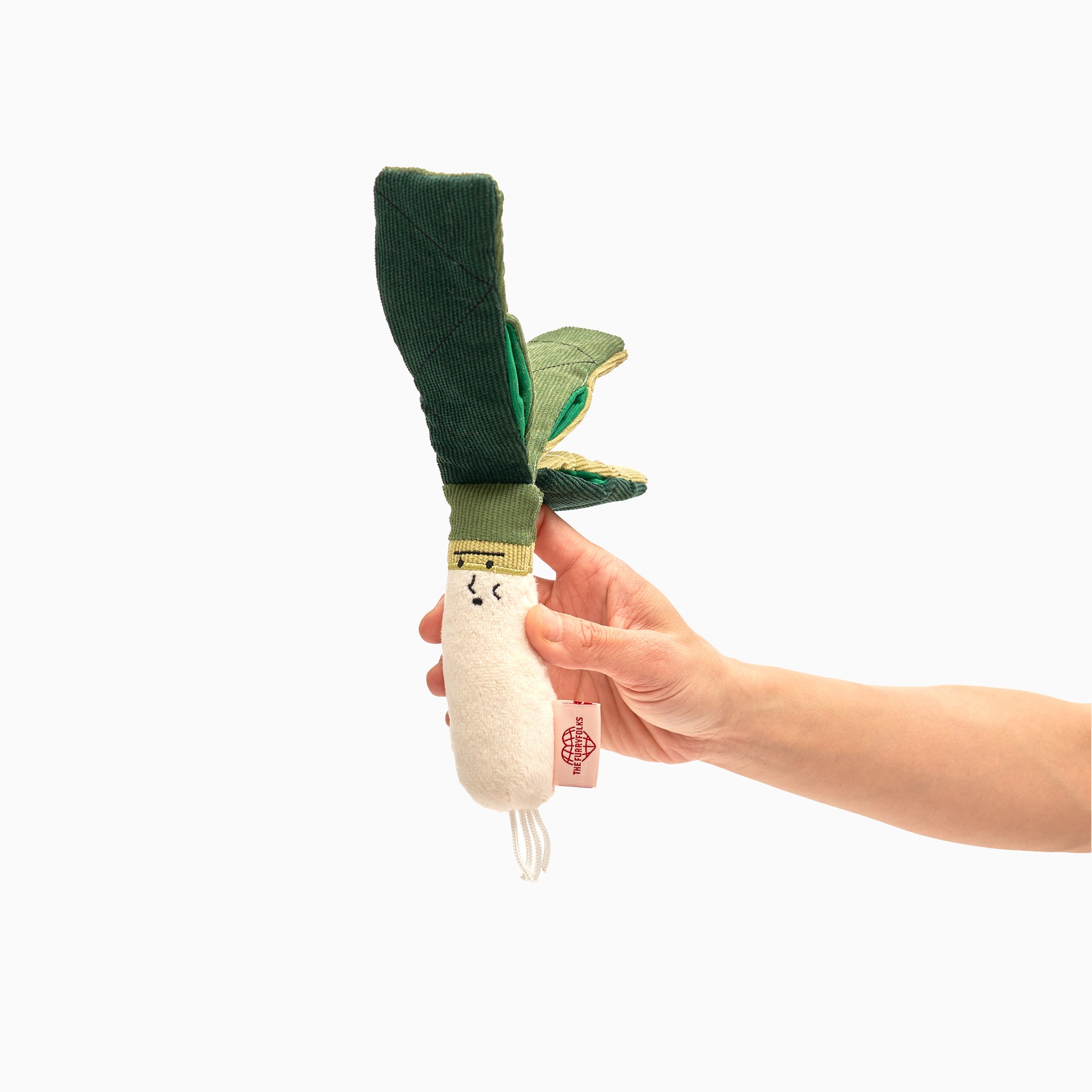 Hand holding a charming green onion dog nosework toy with a smiling face, designed for interactive scent games and cognitive pet training, set against a clean background.