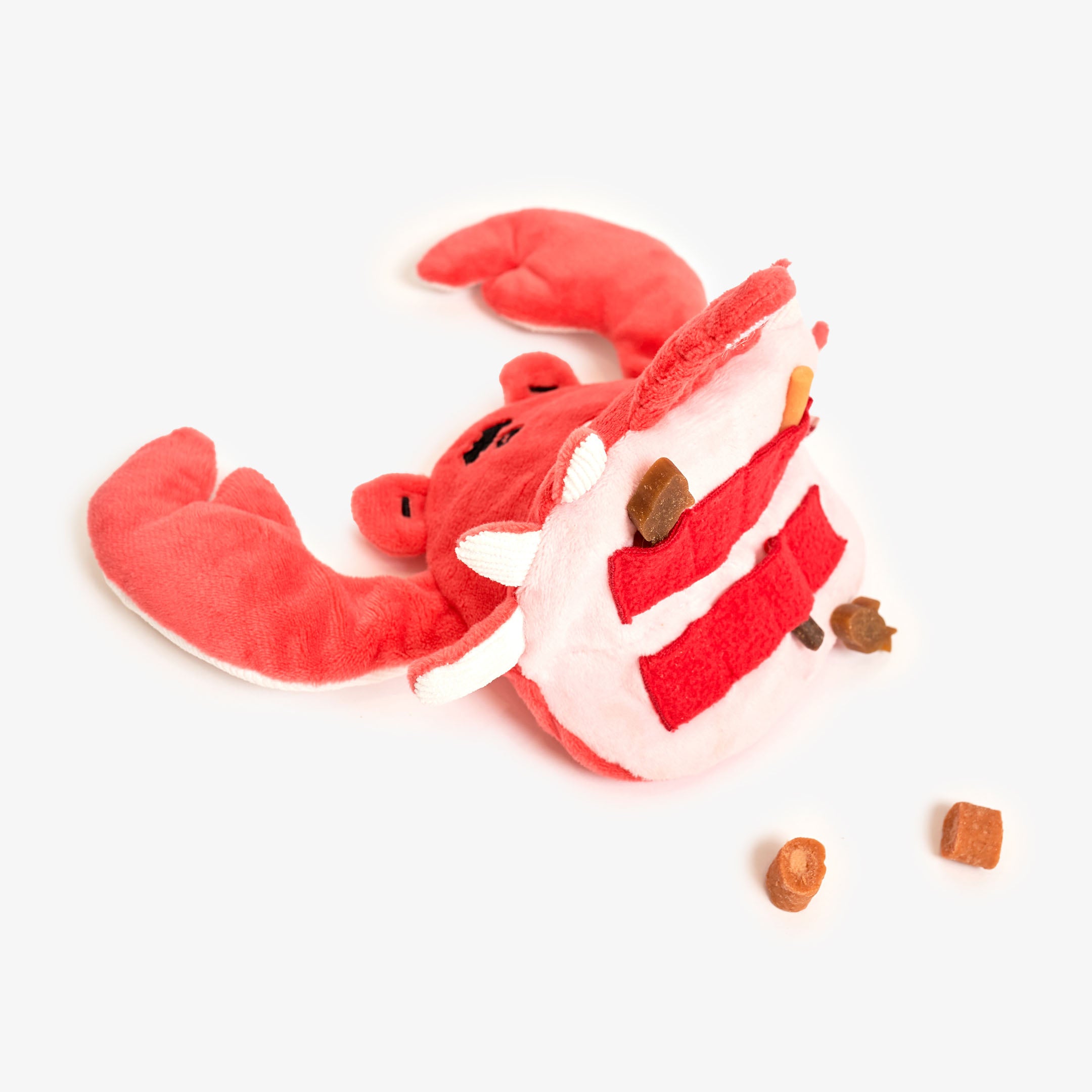 This image shows a red plush crab toy with compartments holding dog treats, an interactive design meant to entertain pets by challenging them to retrieve the snacks.