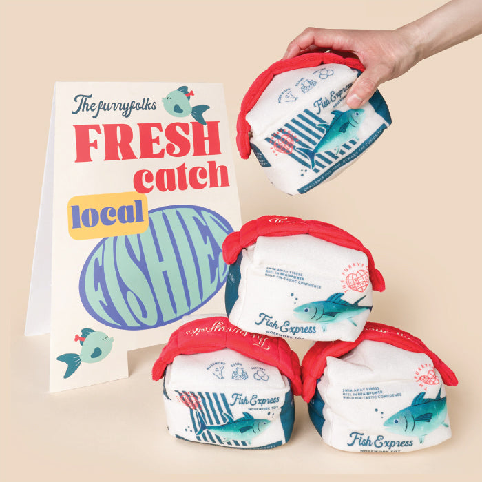 Fish-shaped snack bags with a hand holding one, on a beige background with a sign reading 'Fresh Catch Local Fish'.