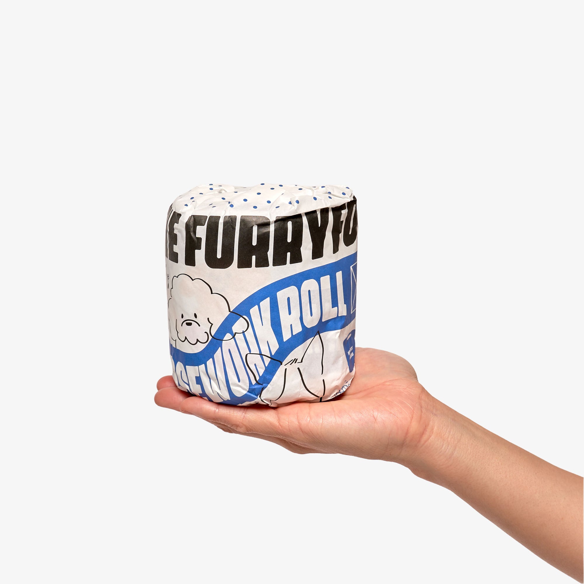 The image shows a hand holding a rolled-up dog toy with a graphic design featuring the text "THE FURRYFOLKS NOSEWORK ROLLS" and an illustration of a fluffy dog. The toy has a blue and white color scheme with a polka dot pattern, and it appears to be made of a fabric material. This design suggests it's part of a line of dog toys focused on scent work and mental stimulation. The neutral background ensures the toy is the central point of focus.