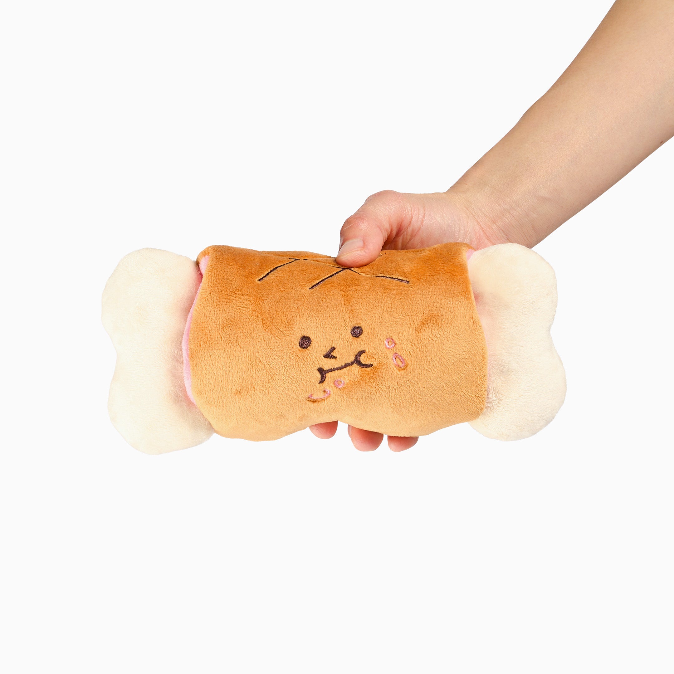 Plush toy resembling a bread roll with a face held by a hand on a white background