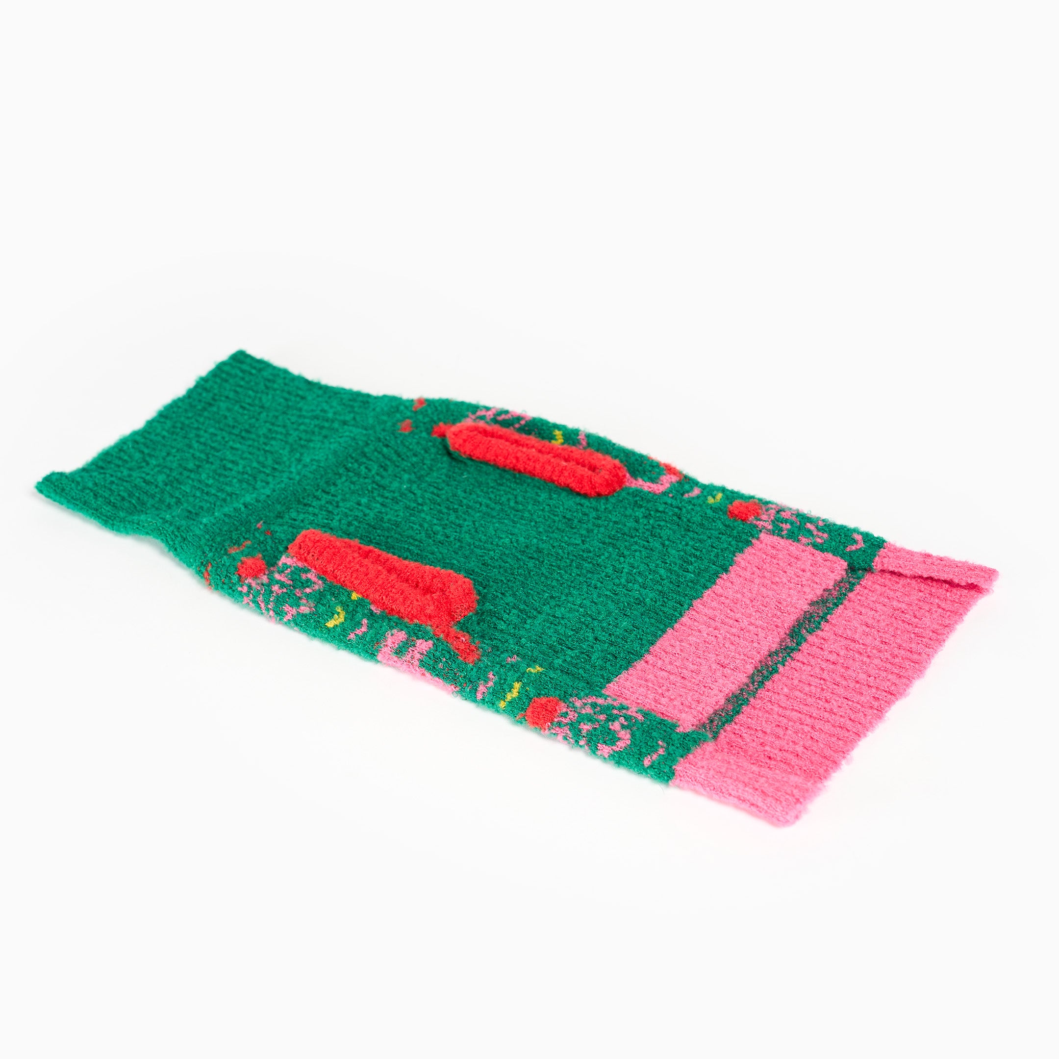 Green, pink, and red knitted dog sweater on a white background