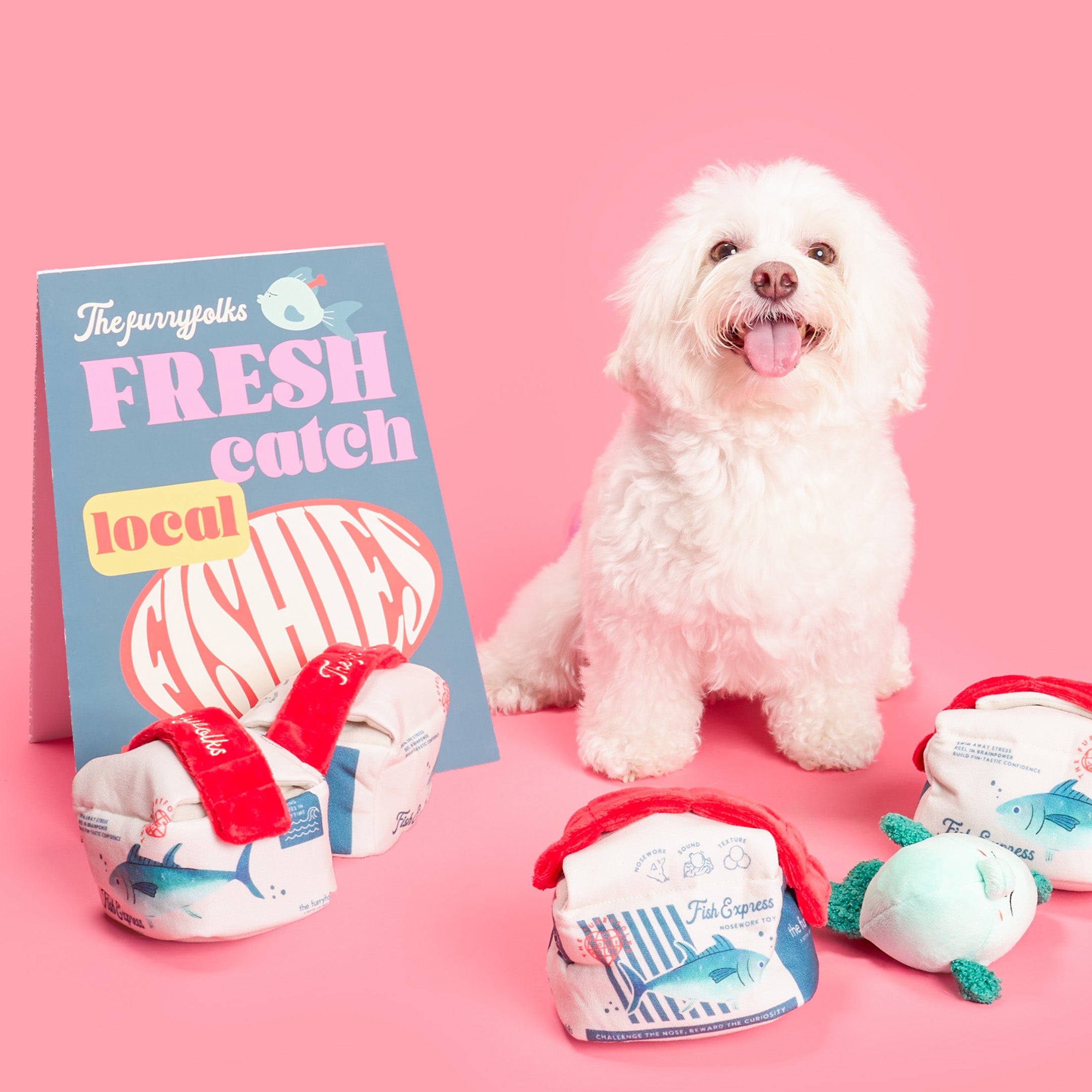 White dog sitting next to a magazine and pet products on a pink background