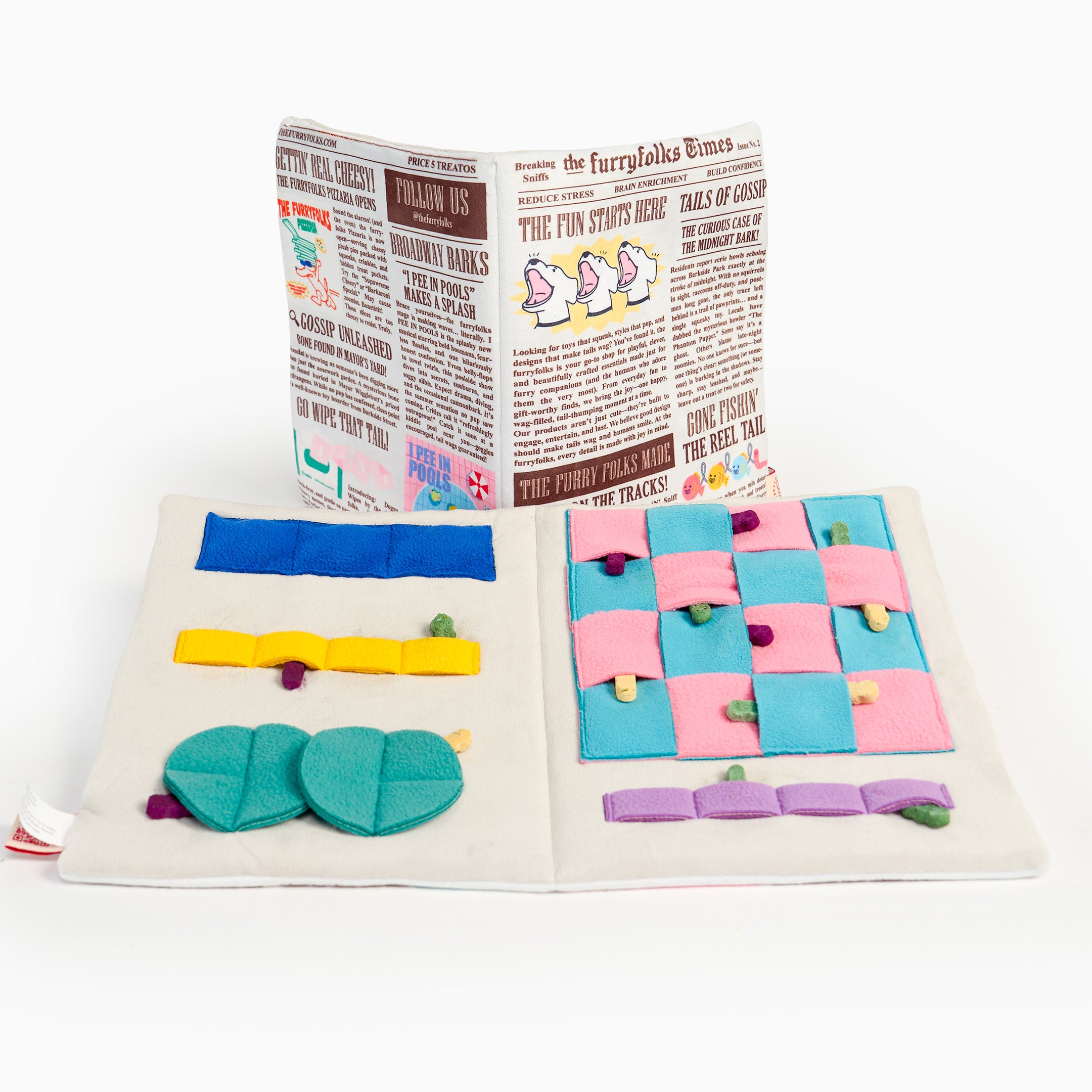 A children's sensory book or activity book shown open on a white background, with colorful fabric buttons, felt shapes, and a newspaper-style cover page visible behind it.