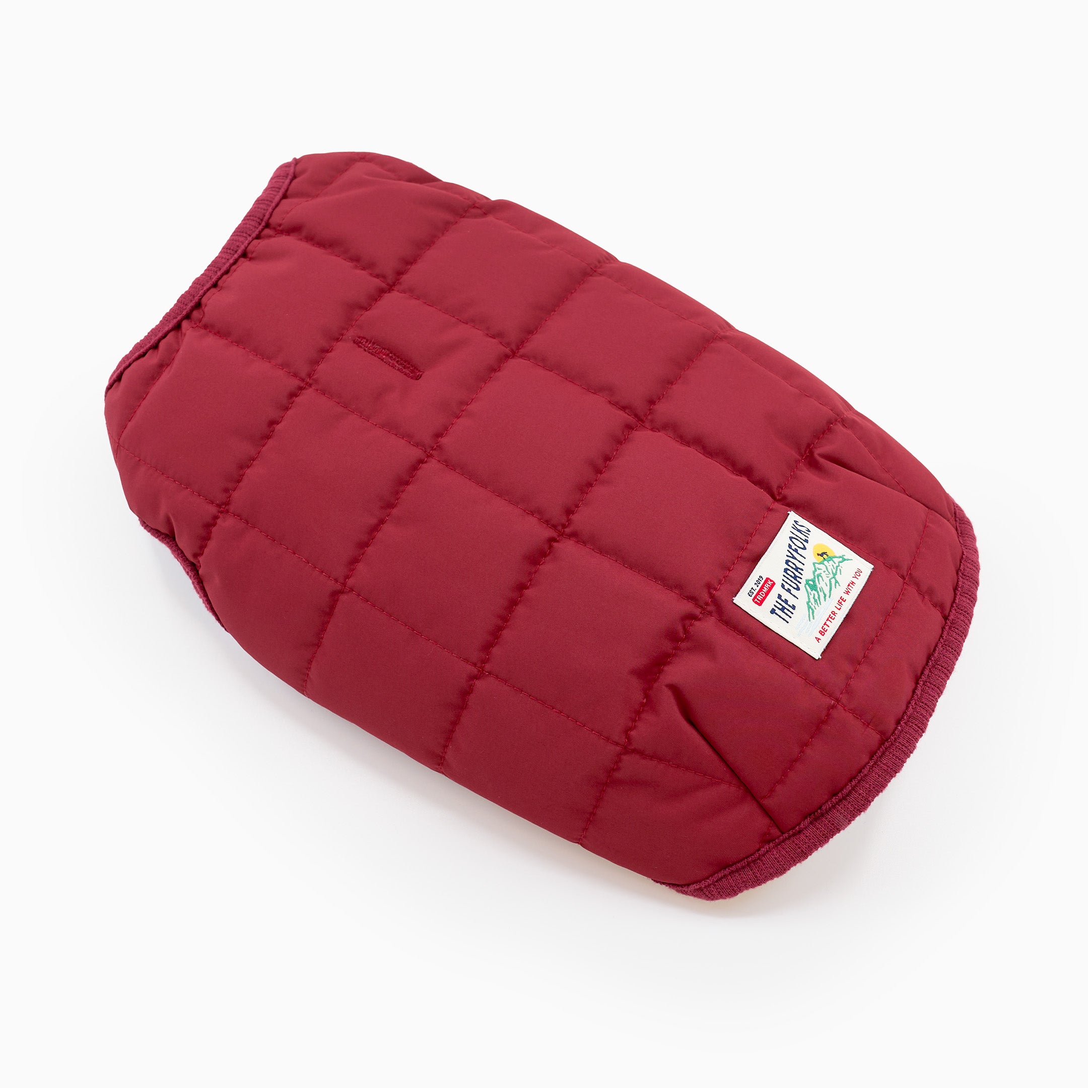 Red quilted dog coat with a brand label on a white background