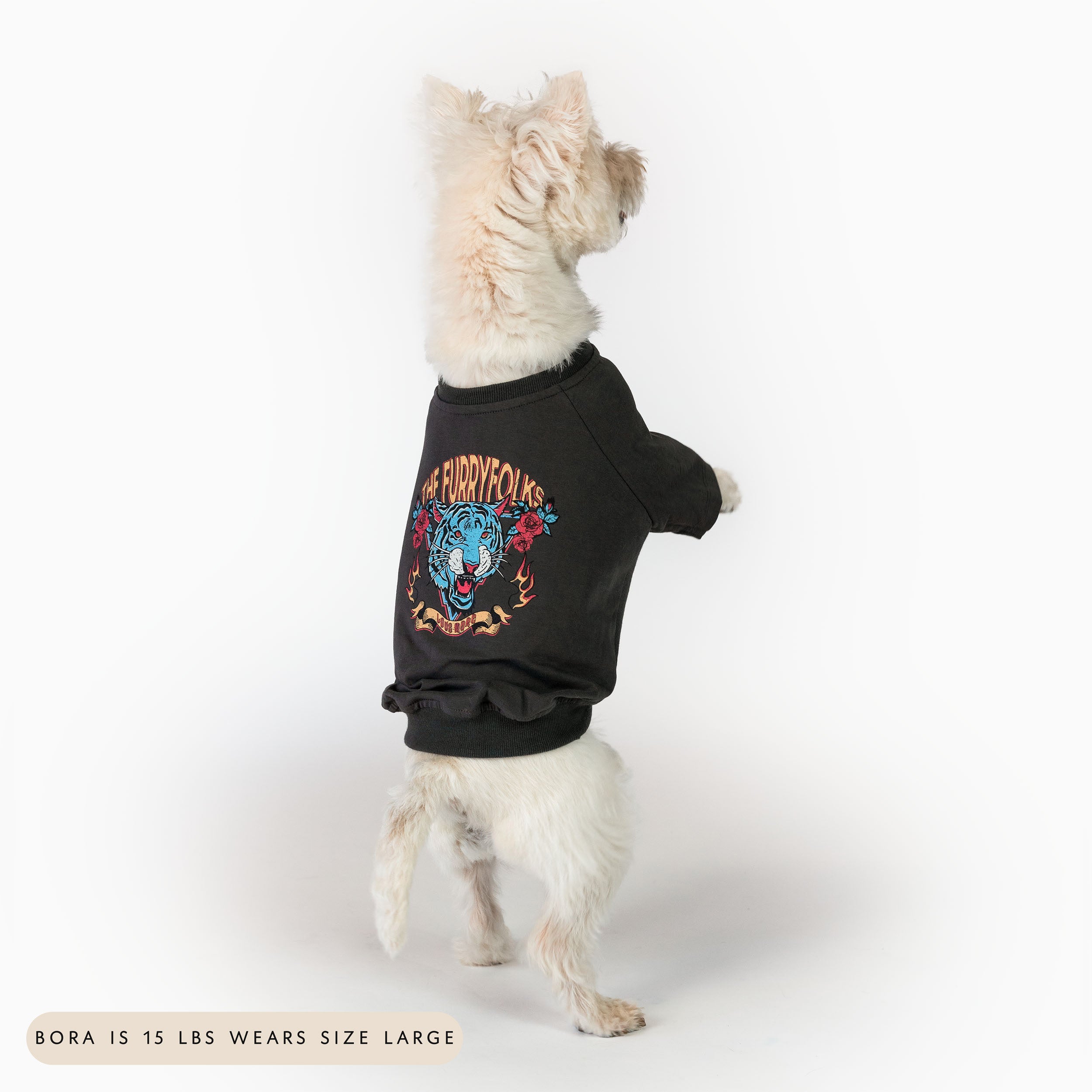 A white dog standing on its hind legs, wearing a size large oversized tiger-themed tee from the furryfolks. The tee features a bold tiger graphic with floral accents, showcasing a stylish and comfortable fit for furry pals