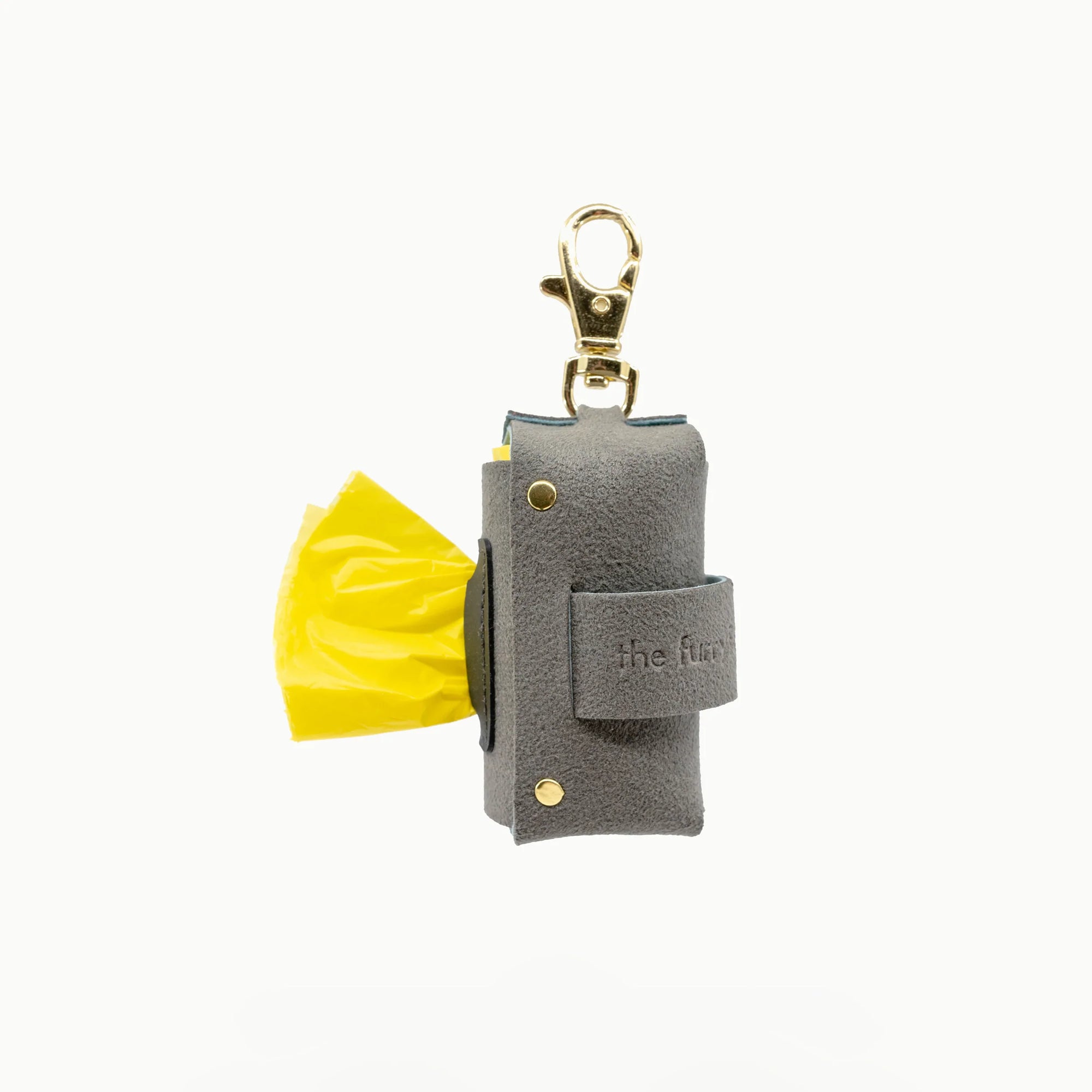 The photo shows a grey dog poop bag holder with a yellow bag protruding, affixed with a gold clip, and stamped with "the furryfolks" brand, designed for ease during dog walks.